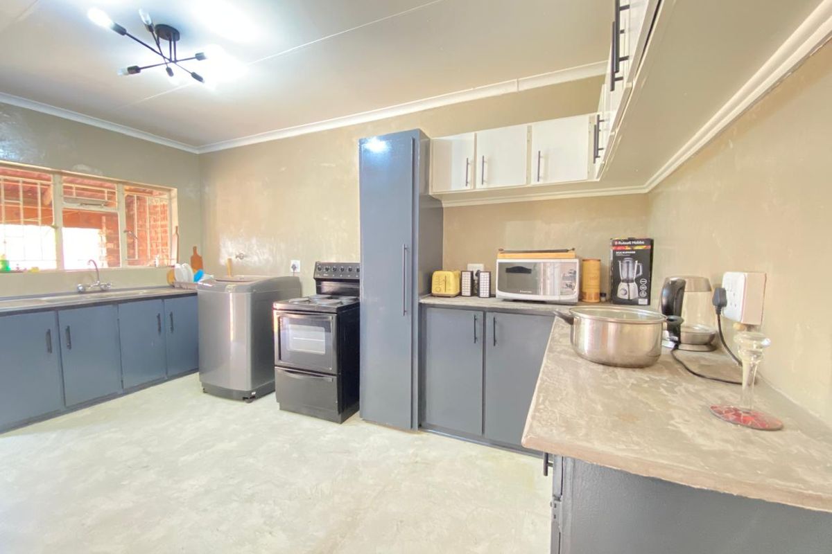 A functional kitchen featuring dark grey cabinetry, a freestanding stove, and a double sink with a window view.