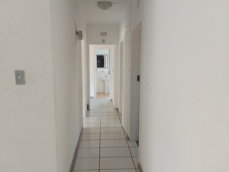 A functional, tiled hallway providing access to multiple rooms, featuring neutral white walls and standard internal door frames.