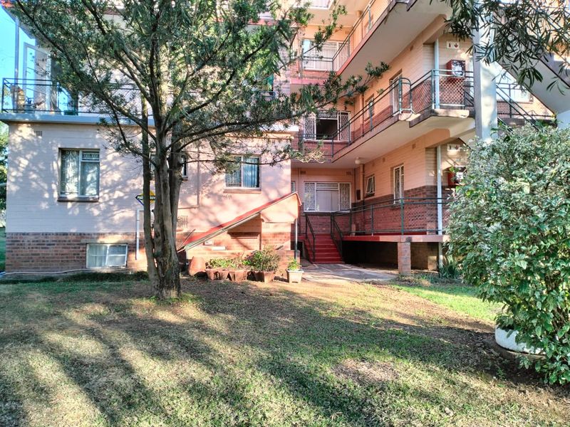 Rear view of a multi-story flat complex featuring brick facade, external staircases, and balcony access with security gates.