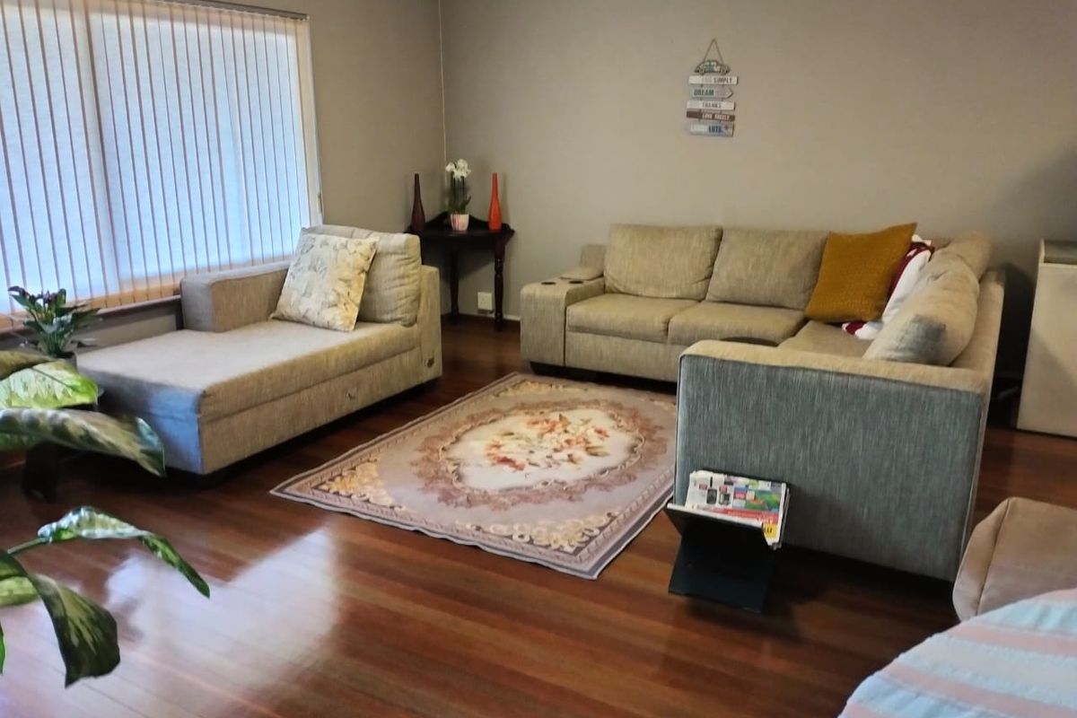 A comfortable living room featuring polished timber flooring and vertical blinds, providing a neutral base for interior design updates.