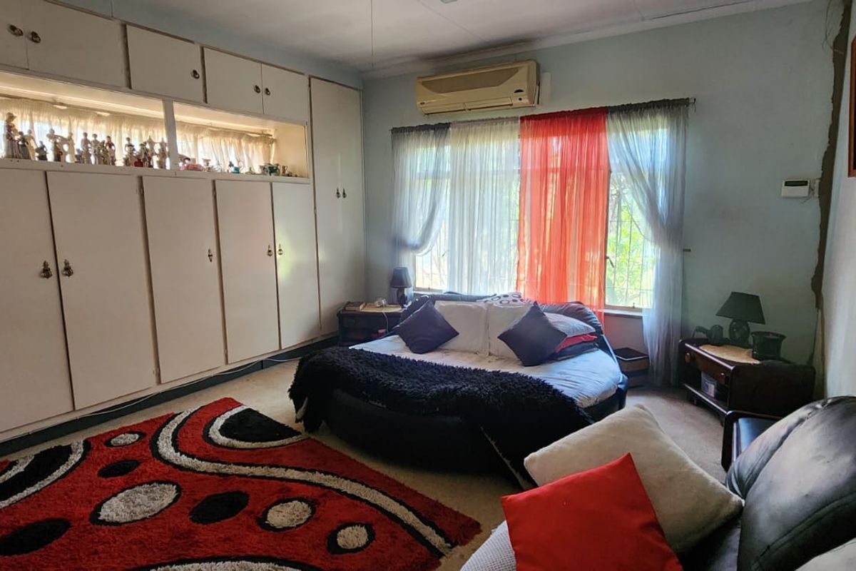 A spacious bedroom featuring extensive built-in cabinetry for storage and a wall-mounted air conditioning unit.