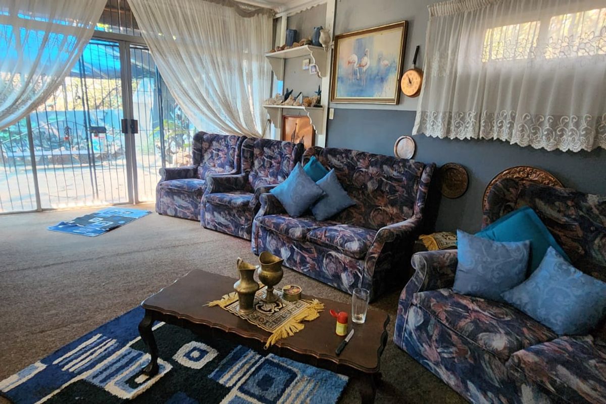 A living room featuring large sliding glass doors leading to an outdoor area, with carpeted flooring and built-in shelving.