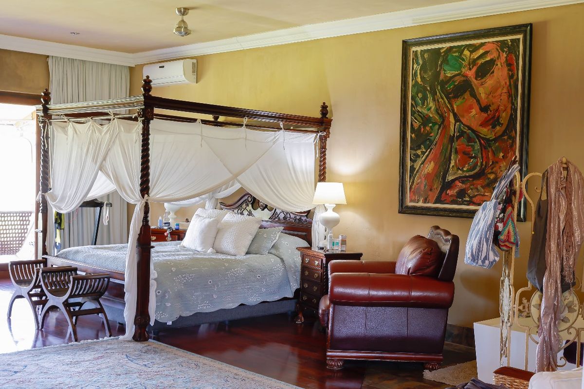 Spacious bedroom featuring dark wood flooring, crown molding, and a wall-mounted air conditioning unit, with direct access to an outdoor patio area.