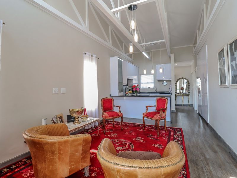 Spacious open-plan living area featuring vaulted ceilings with exposed trusses, modern kitchen cabinetry, and durable laminate flooring in a bright, well-maintained retirement unit.