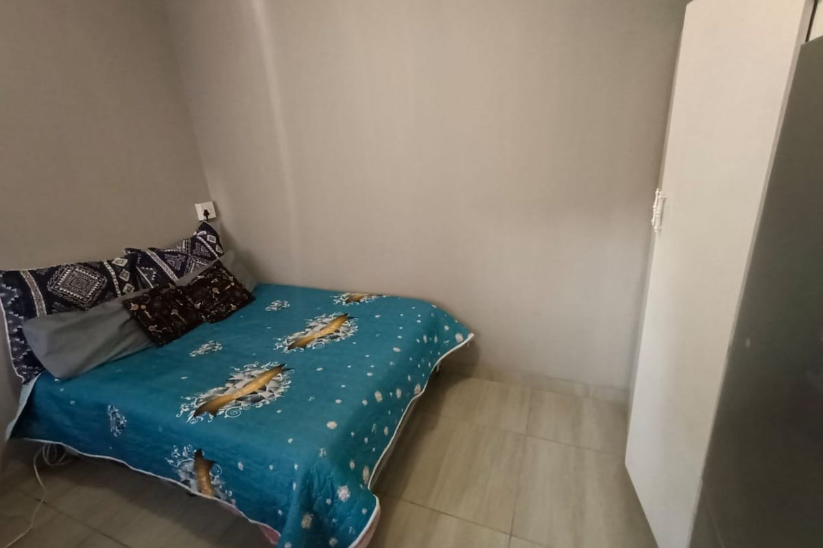 A functional bedroom featuring tiled flooring and neutral wall finishes, providing a simple and practical living space.