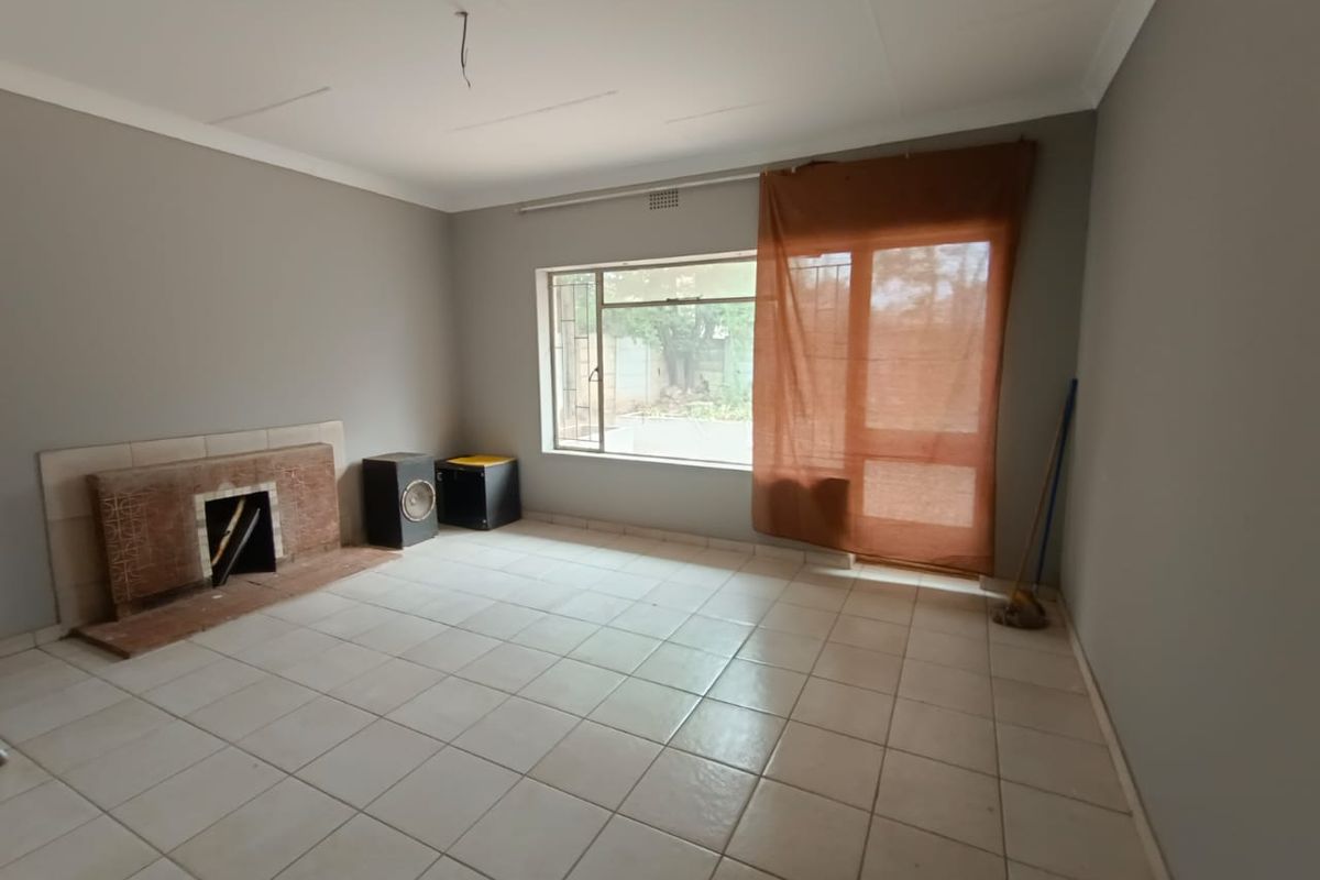 A spacious, empty living room featuring neutral wall paint, tiled flooring, and a built-in fireplace, offering a blank canvas for personalization.