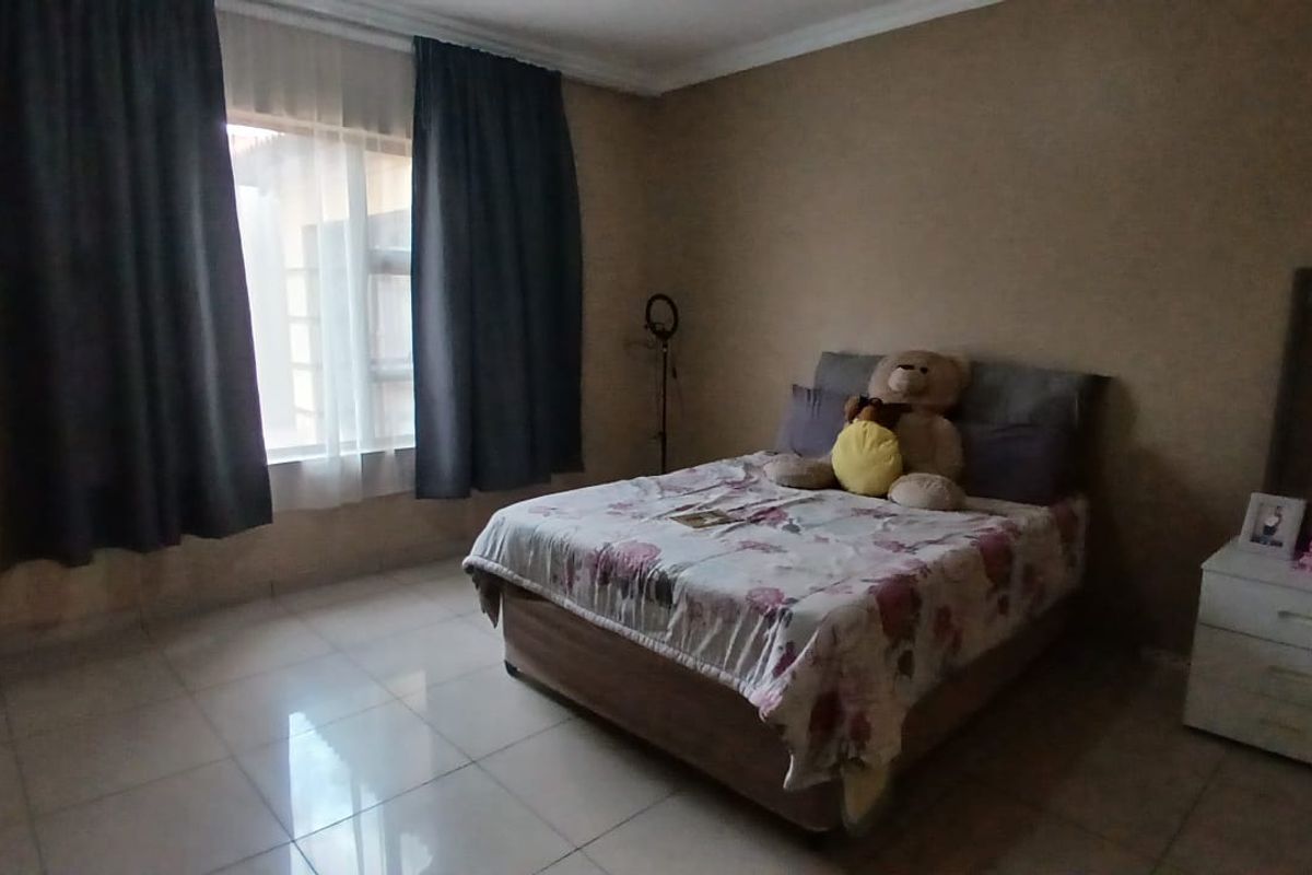 A bedroom featuring tiled flooring and large windows with curtains, providing natural light to the space.