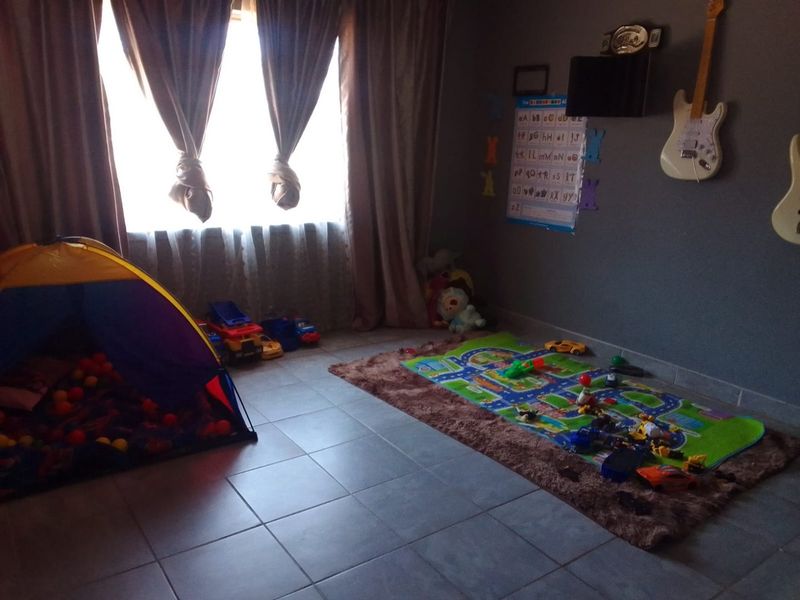 A bedroom featuring tiled flooring and neutral wall finishes, currently utilized as a children's play area.