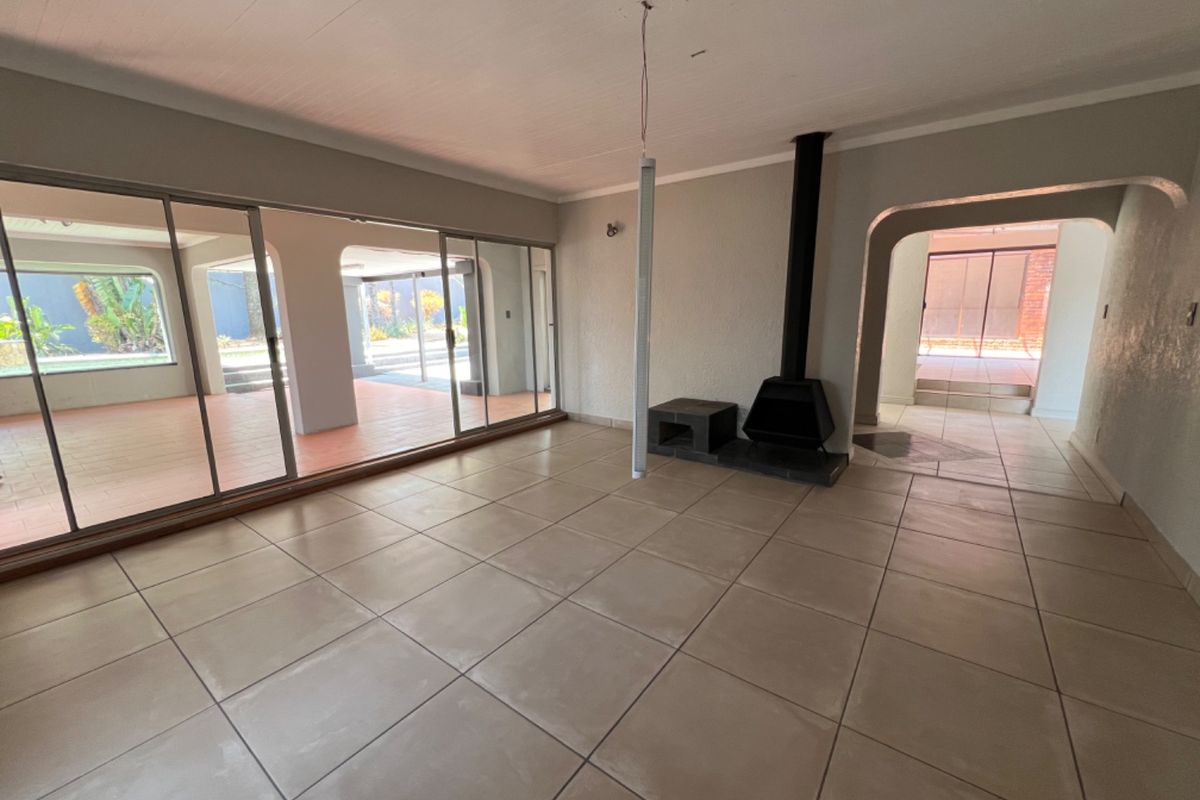 Spacious living area featuring large sliding glass doors, tiled flooring, and a built-in fireplace, offering seamless access to the outdoor patio.