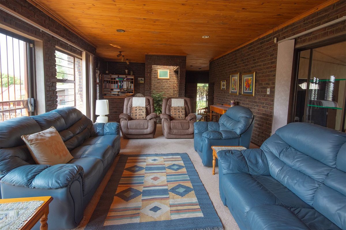 Spacious living room featuring exposed face-brick walls, a warm timber-clad ceiling, and large windows allowing for natural light.