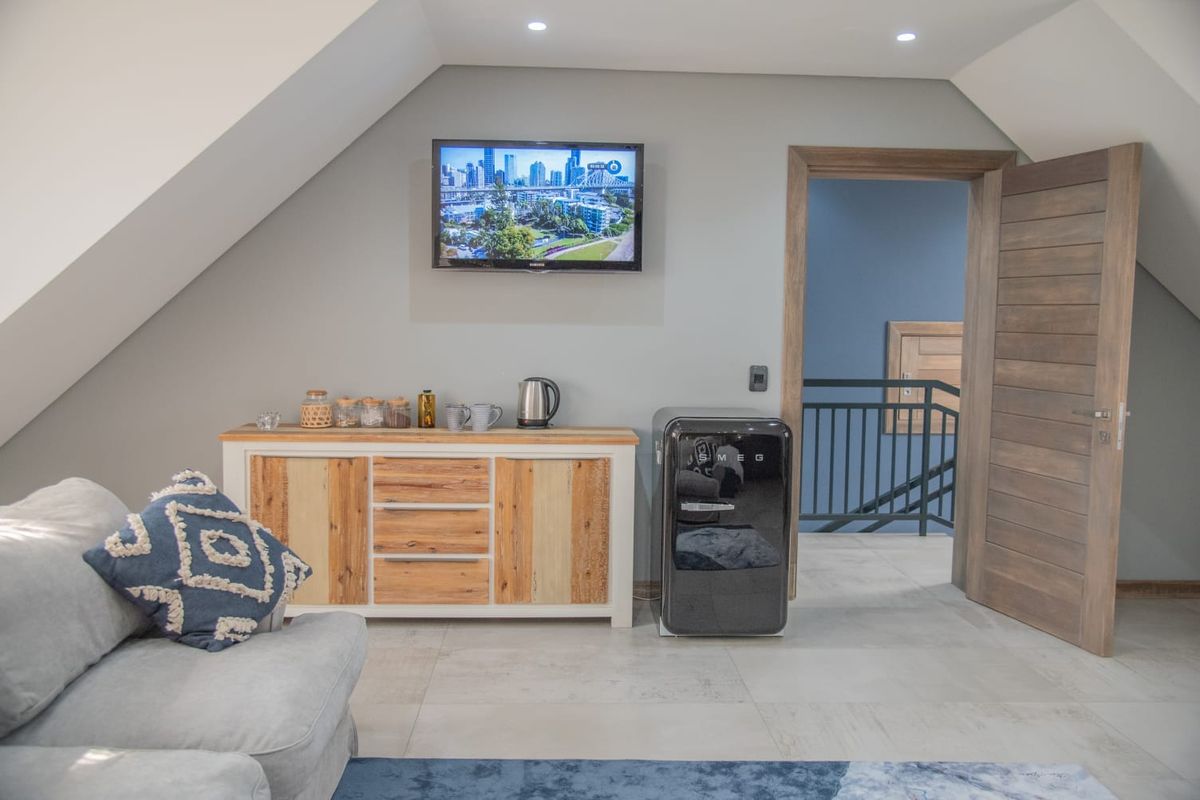 A well-maintained living area featuring tiled flooring, recessed ceiling lighting, and a doorway leading to a staircase with a metal balustrade.