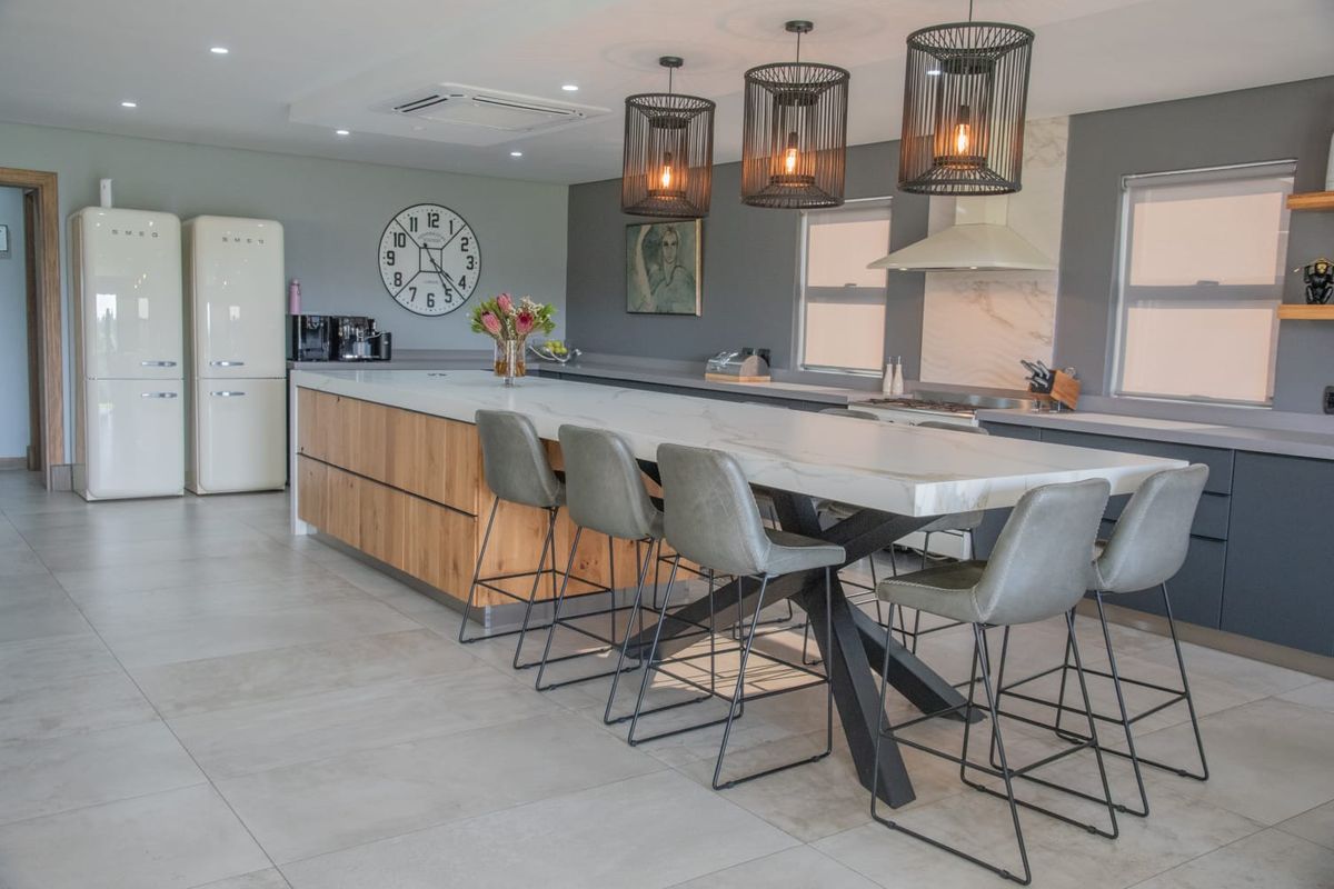 Modern kitchen featuring a large central island with stone countertop, integrated cabinetry, and contemporary pendant lighting.