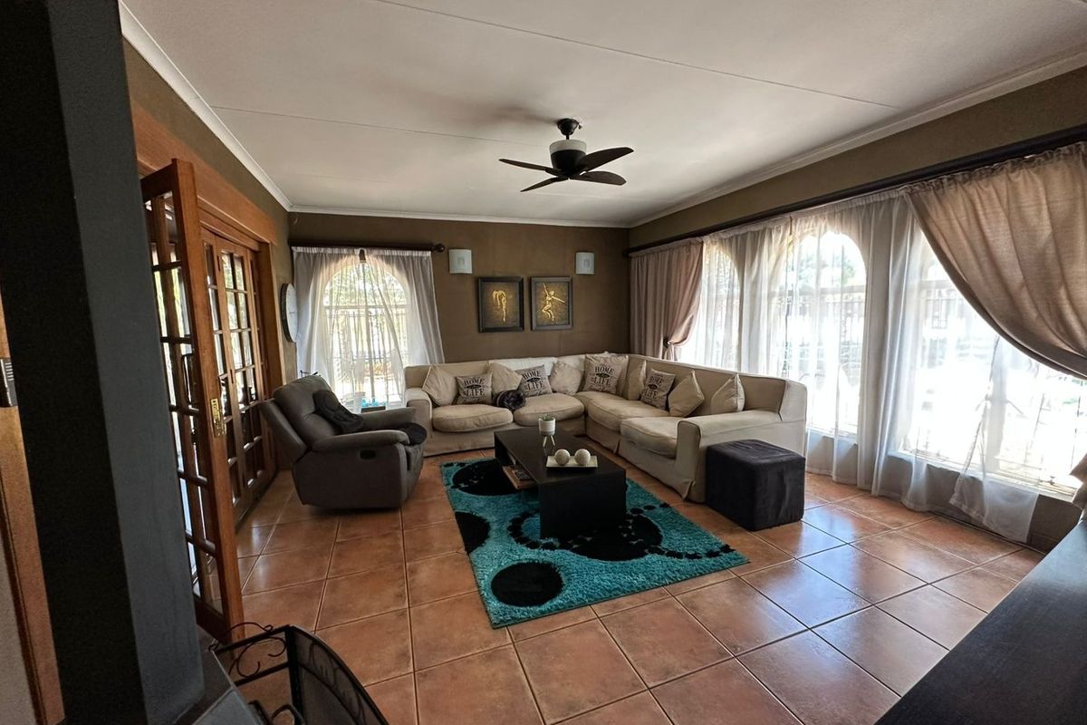 Spacious living room featuring tiled flooring, a ceiling fan, and large arched windows that provide ample natural light.