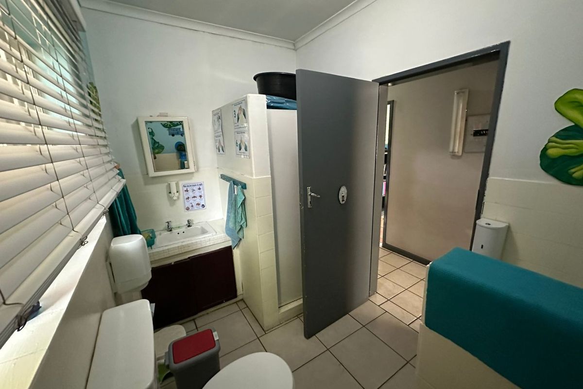 A functional bathroom featuring a tiled vanity, toilet, and shower area with neutral finishes and practical layout.