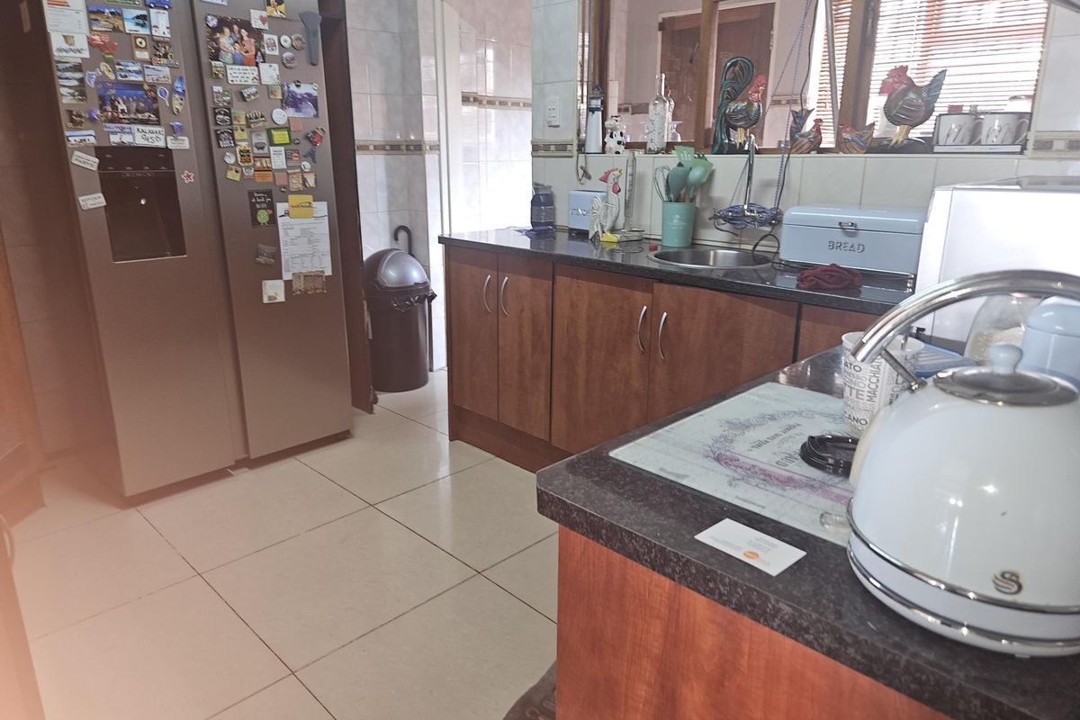 A functional kitchen featuring laminate cabinetry, granite countertops, a stainless steel sink, and tiled flooring with a tiled backsplash.