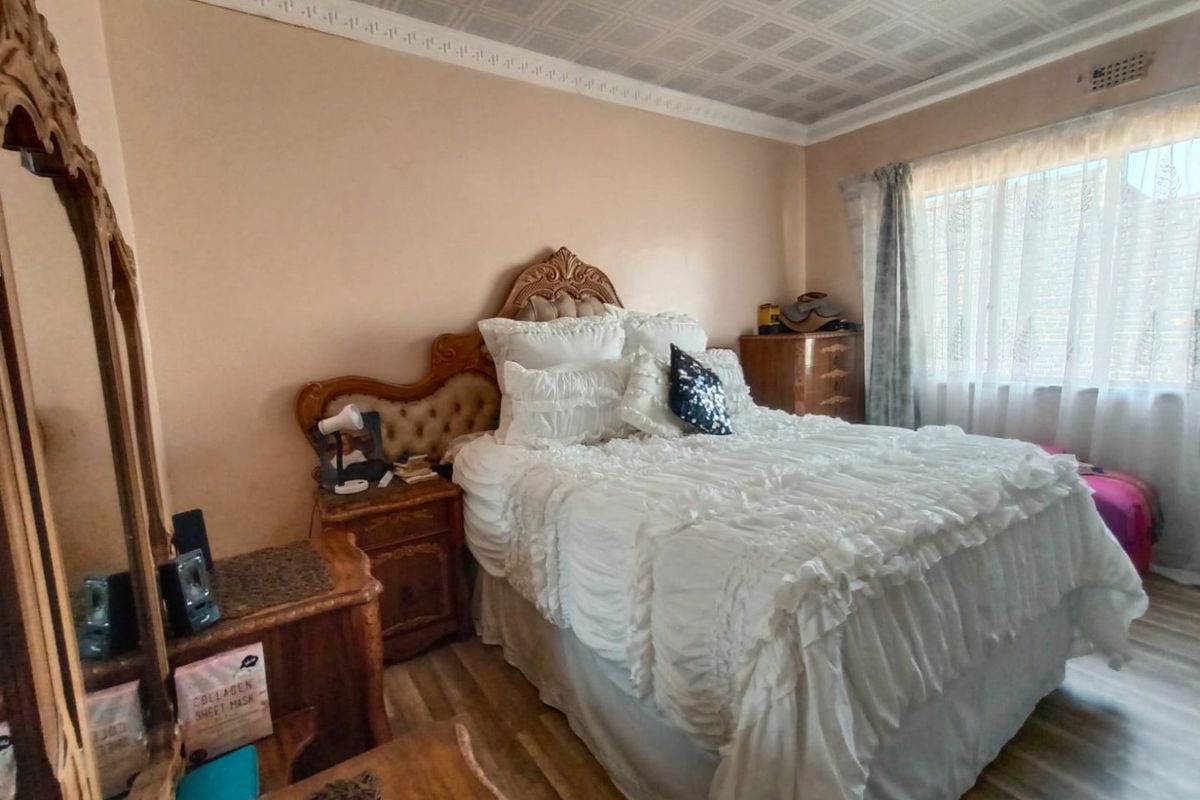 A bedroom featuring decorative ceiling tiles, crown molding, and wood-look flooring, providing a functional space with traditional architectural details.