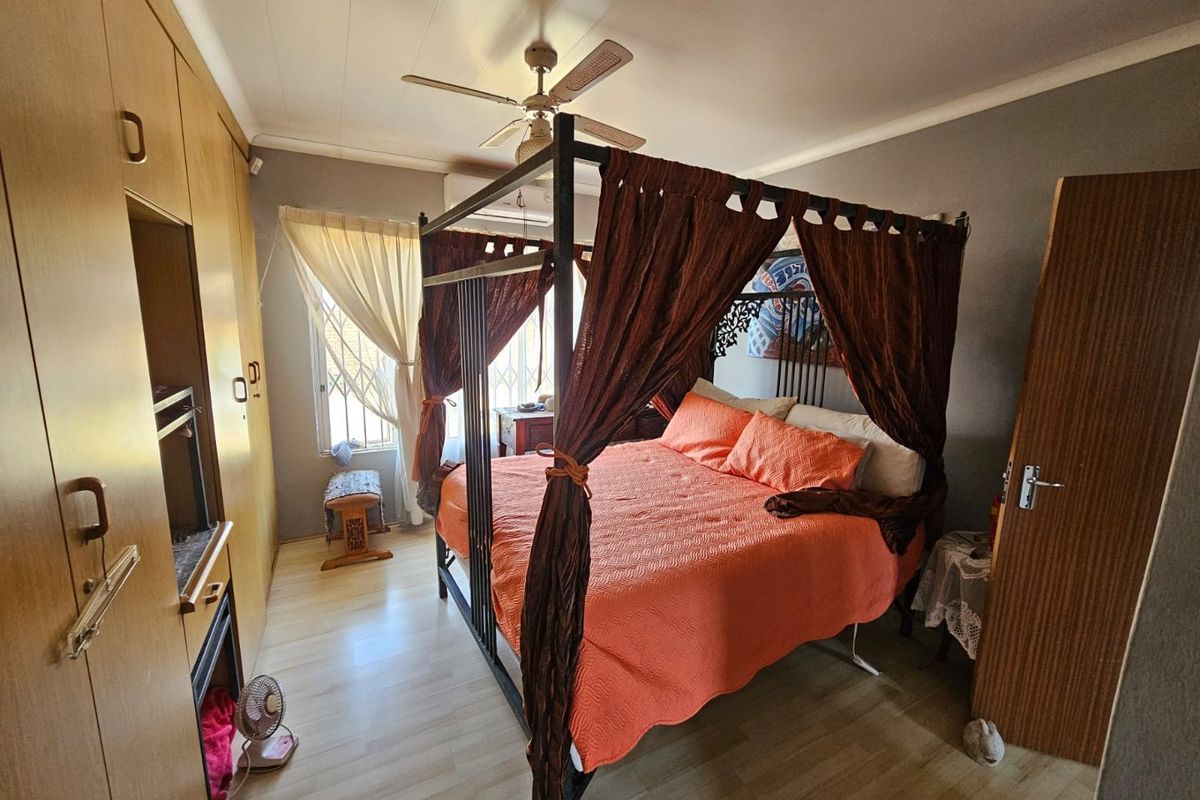 A bedroom featuring built-in wooden wardrobes, laminate flooring, and a ceiling fan, providing a functional and comfortable living space.