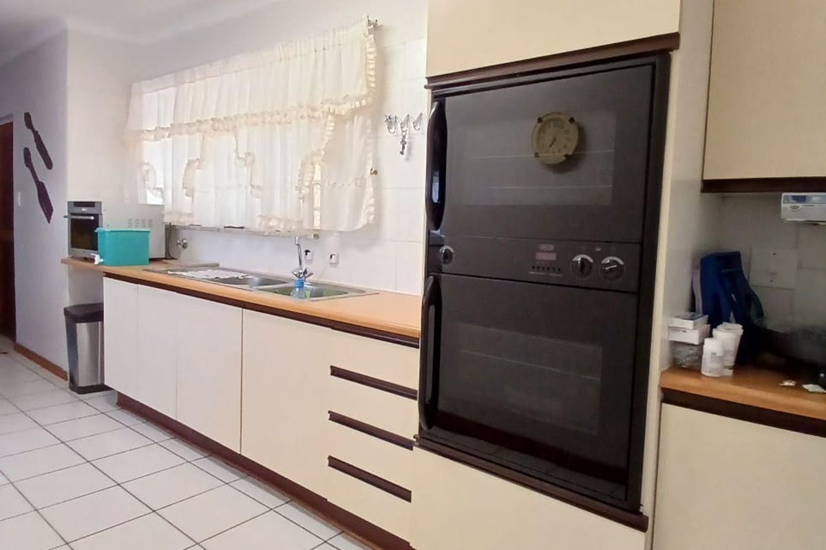 A functional kitchen featuring built-in double ovens, laminate countertops, tiled flooring, and ample cabinetry for storage.