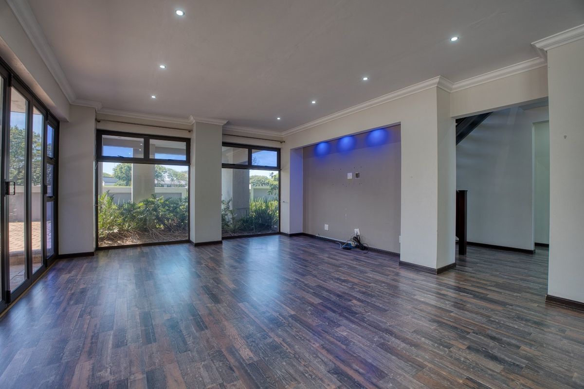 Spacious, empty living area featuring dark laminate flooring, recessed downlights, and a built-in media alcove with integrated accent lighting.