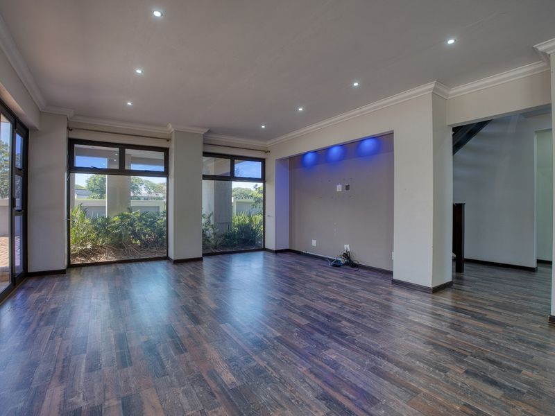 Spacious, empty living area featuring dark laminate flooring, recessed downlights, and a built-in media alcove with integrated accent lighting.