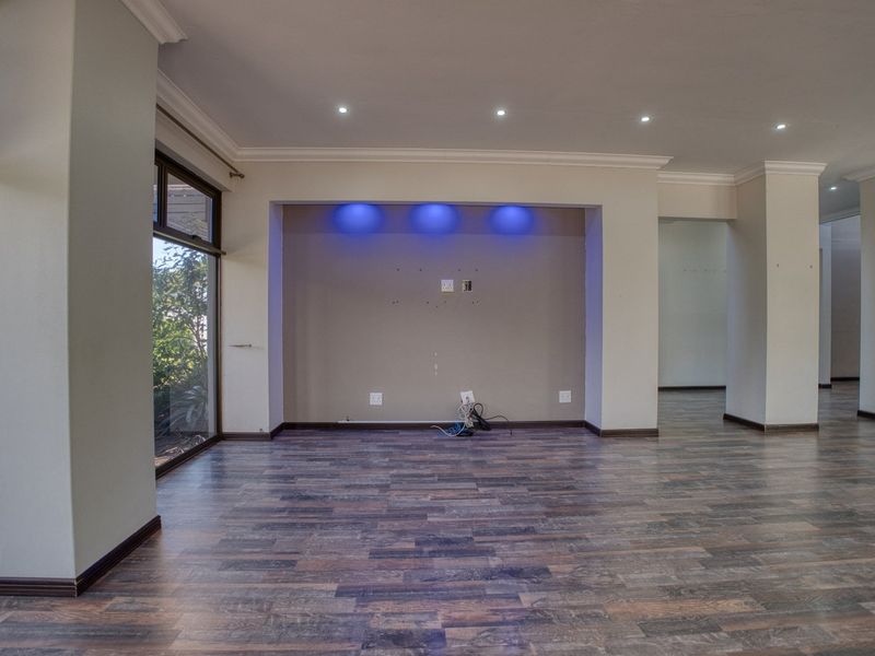 Spacious, empty living area featuring laminate flooring, recessed downlights, and a built-in media alcove with integrated accent lighting.