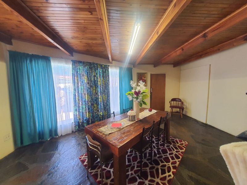 Dining room featuring rustic slate tile flooring and a vaulted timber beam ceiling, providing a warm and traditional atmosphere.