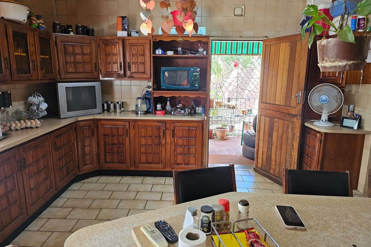 A dated kitchen featuring traditional wooden cabinetry, tiled flooring, and direct access to an outdoor patio area.