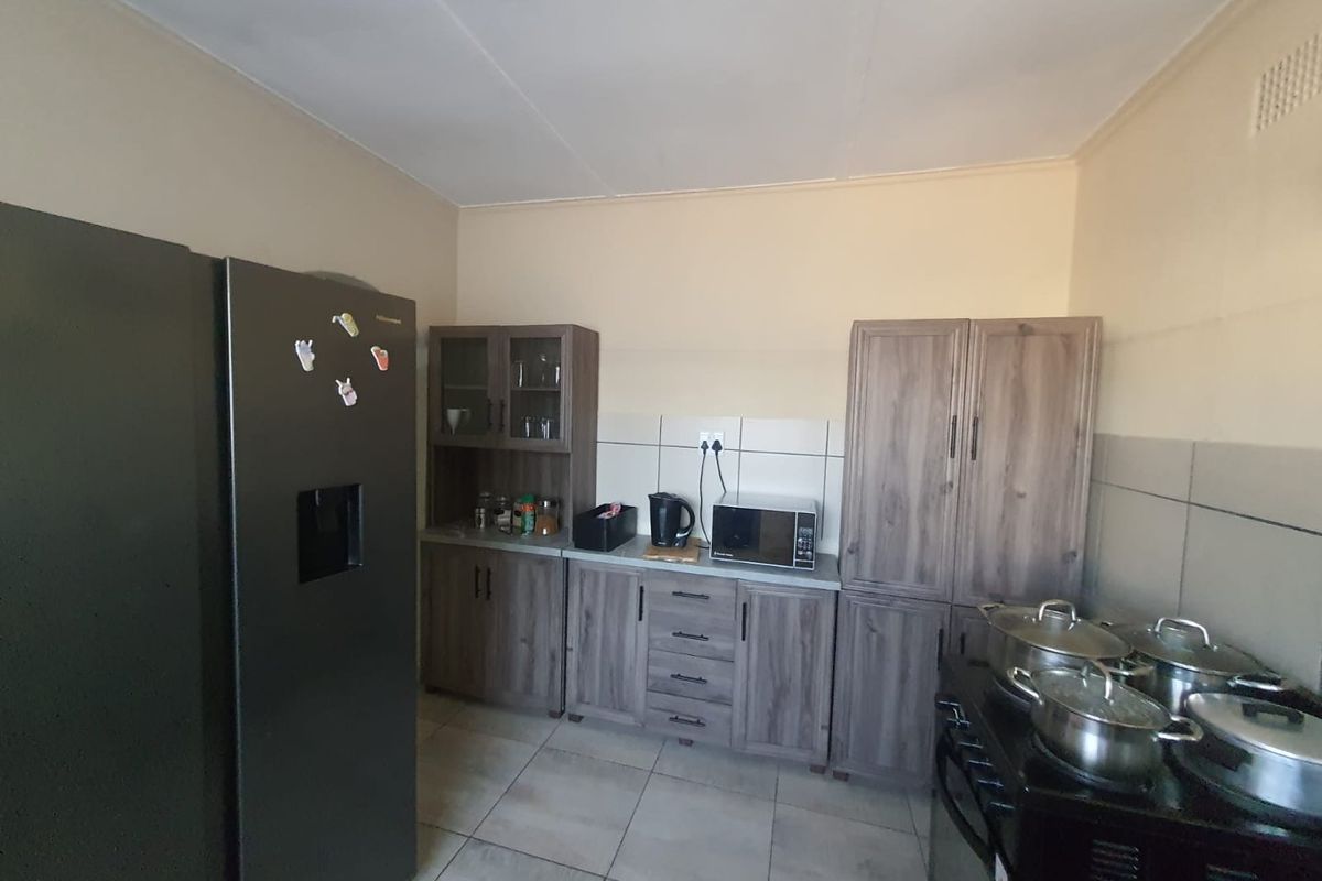 A functional kitchen featuring wood-look cabinetry, tiled flooring, and tiled splashbacks, providing ample storage and workspace for daily meal preparation.