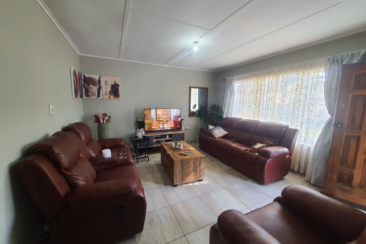 A comfortable living room featuring tiled flooring, neutral wall tones, and large windows that provide ample natural light.