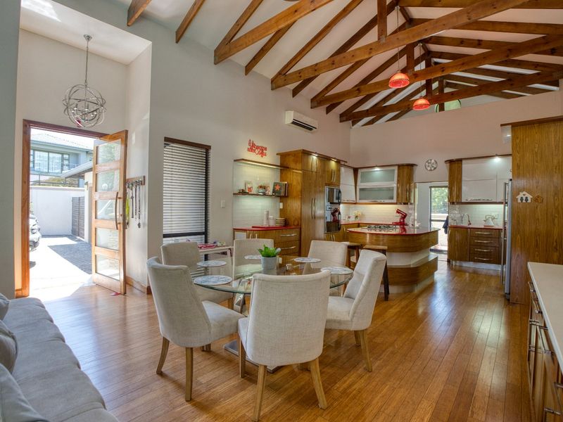 Spacious open-plan living and kitchen area featuring high vaulted ceilings with exposed timber trusses, hardwood flooring, and a functional kitchen island.