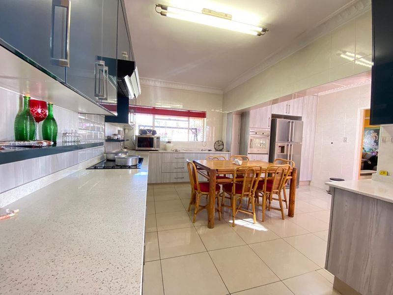 Spacious open-plan kitchen and dining area featuring modern cabinetry, quartz countertops, tiled flooring, and integrated built-in appliances.
