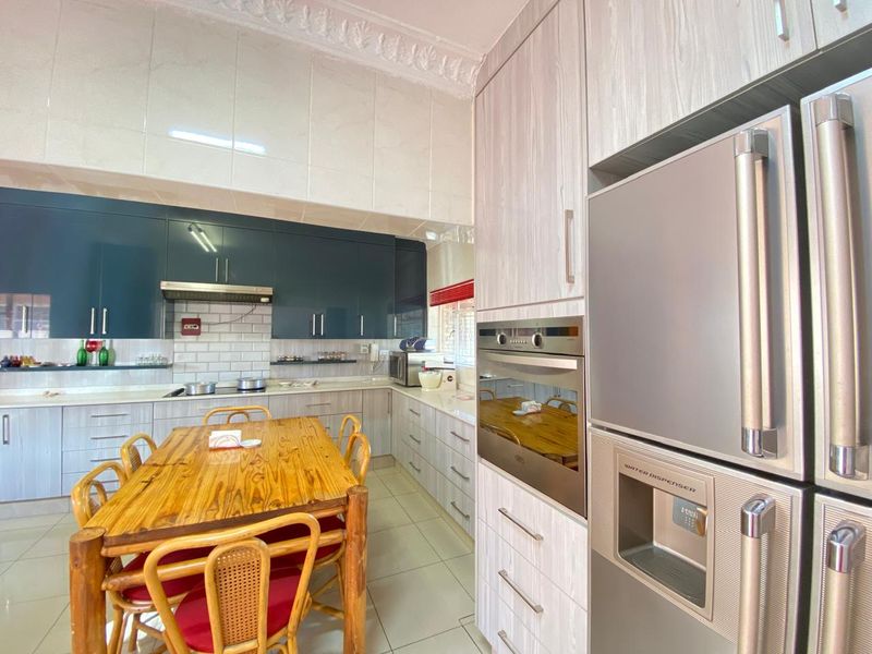 Modern kitchen featuring two-tone cabinetry, built-in oven, extractor fan, tiled splashbacks, and tiled flooring with decorative ceiling cornice.