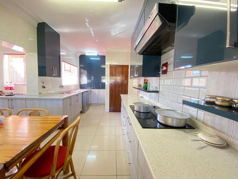 Modern kitchen featuring sleek dark cabinetry, light quartz countertops, subway tile backsplash, and integrated electric hob with extractor fan.
