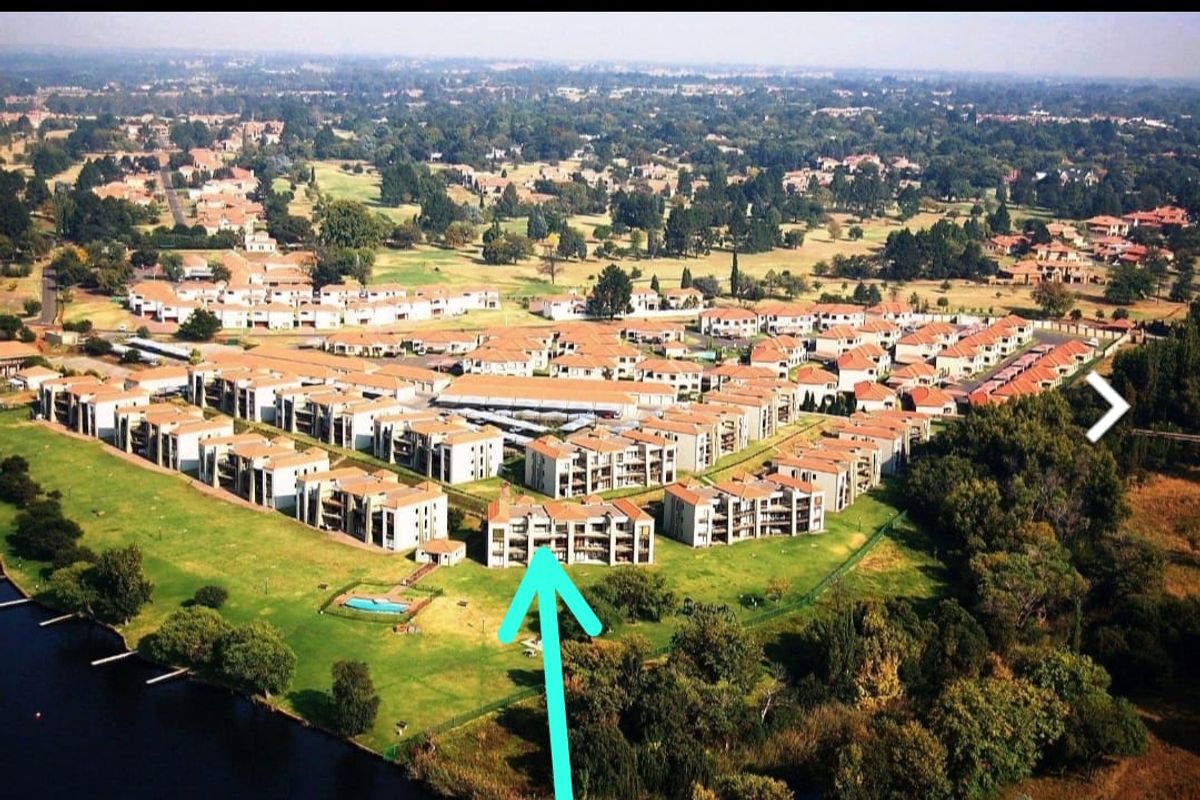 Aerial view of the residential complex featuring multiple apartment blocks, landscaped grounds, and proximity to a water body and golf course.