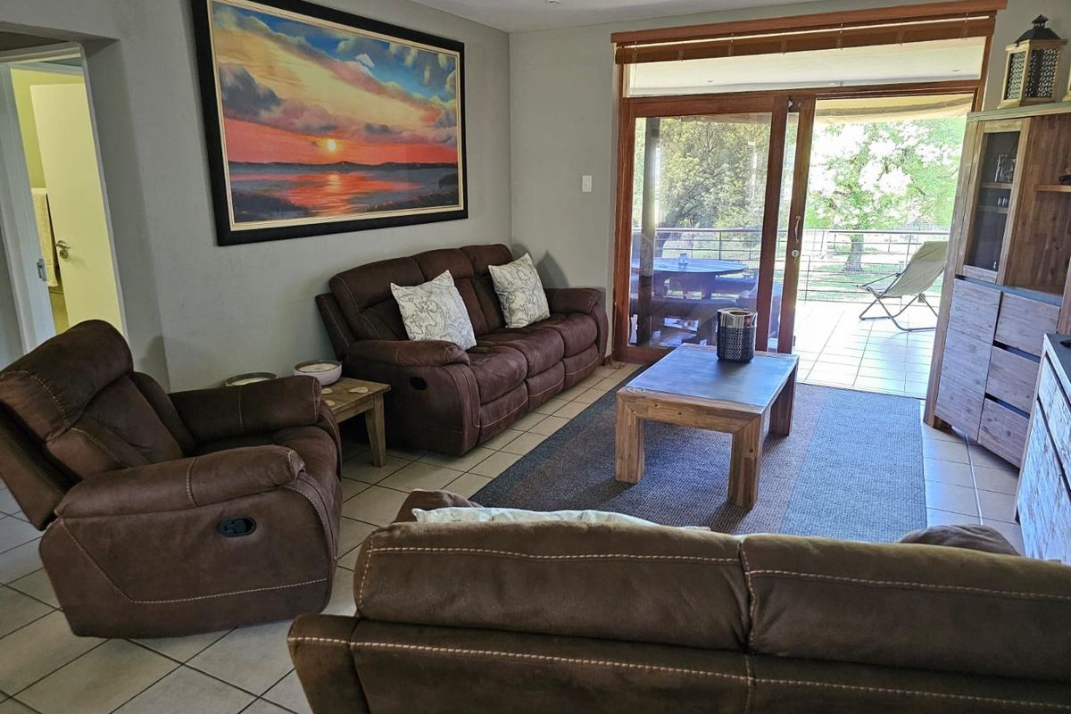A comfortable living room featuring tiled flooring and large sliding glass doors that open onto a private balcony with outdoor seating.