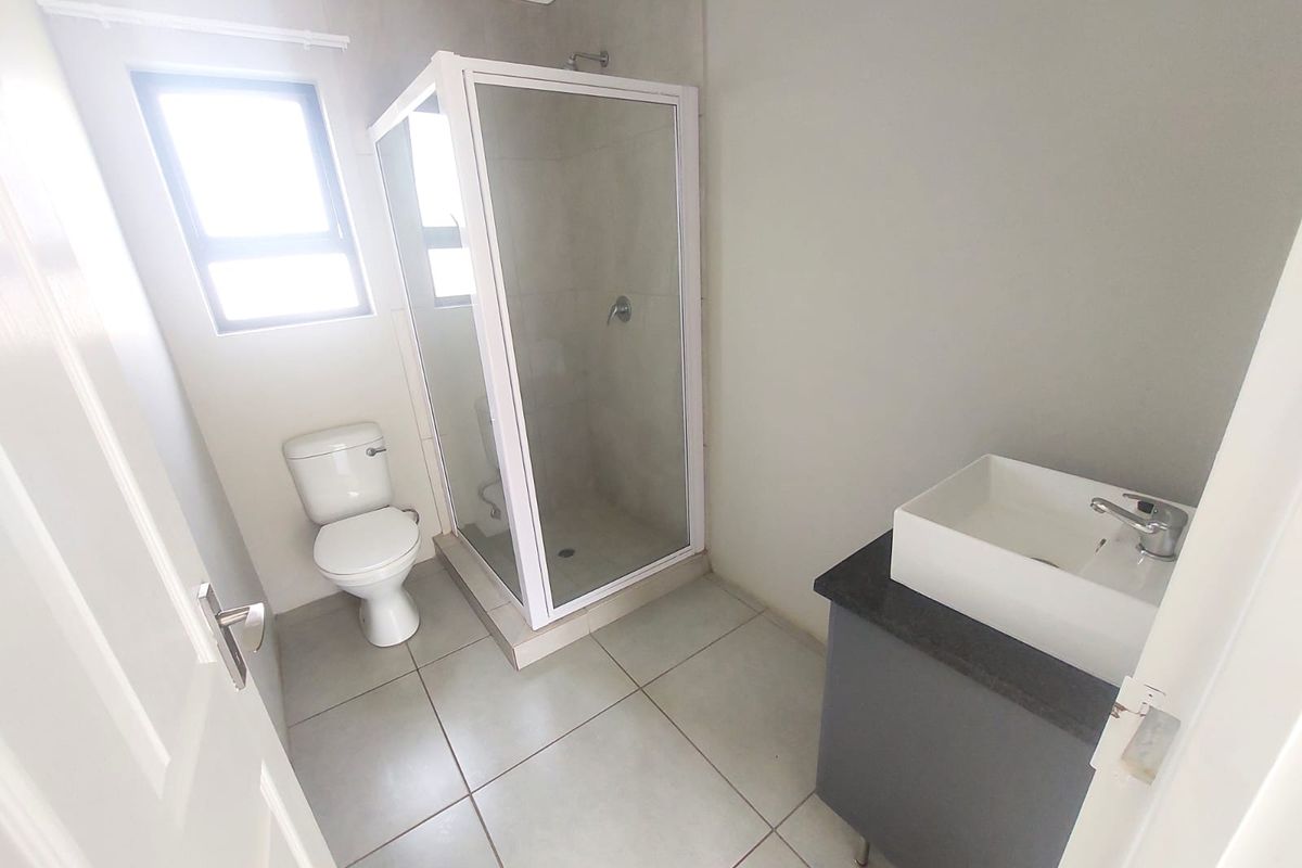 A clean, modern bathroom featuring a glass-enclosed shower, a white ceramic toilet, and a contemporary vanity with a vessel sink.