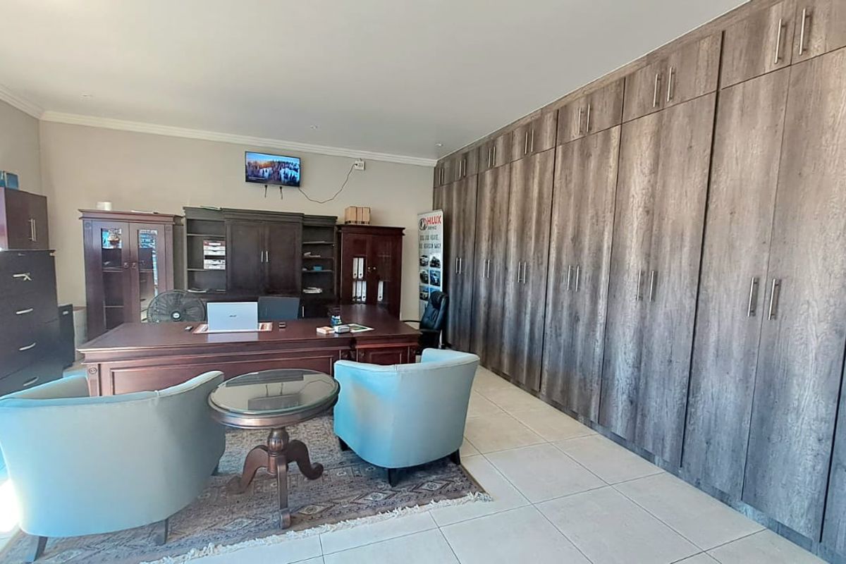 A spacious office featuring extensive floor-to-ceiling built-in wooden cabinetry, tiled flooring, and recessed lighting, providing ample storage and a professional workspace environment.