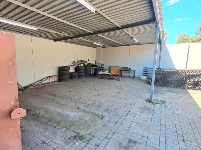 A spacious covered outdoor utility or storage area featuring paved flooring, metal roofing, and perimeter walling, suitable for various commercial or industrial storage needs.