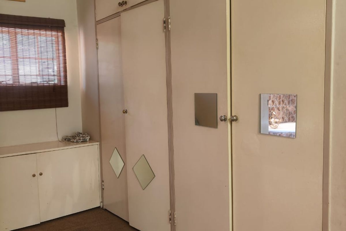 Bedroom featuring extensive built-in floor-to-ceiling cabinetry with integrated storage and a low-level side cabinet under a window with blinds.