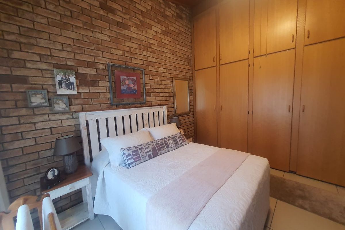 A bedroom featuring a rustic exposed brick feature wall and extensive built-in wooden cabinetry providing ample storage space.
