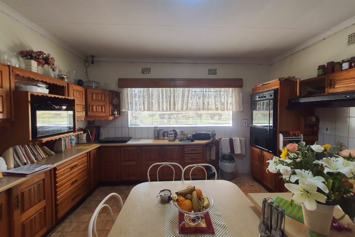 A functional kitchen featuring traditional wooden cabinetry, integrated wall oven, built-in microwave, and a central dining area with tiled flooring.