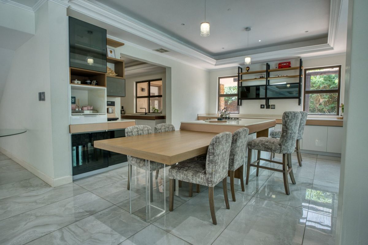 Modern kitchen featuring a central island with integrated dining space, sleek cabinetry, stone countertops, and polished porcelain floor tiles.