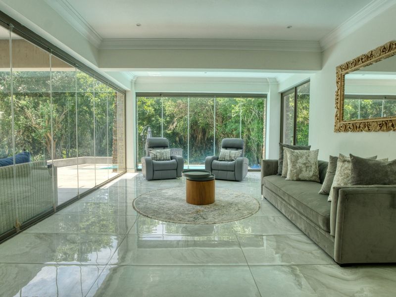 Spacious living room featuring large format porcelain tiles, coved ceilings, and expansive frameless glass stacking doors providing seamless indoor-outdoor flow to the garden.