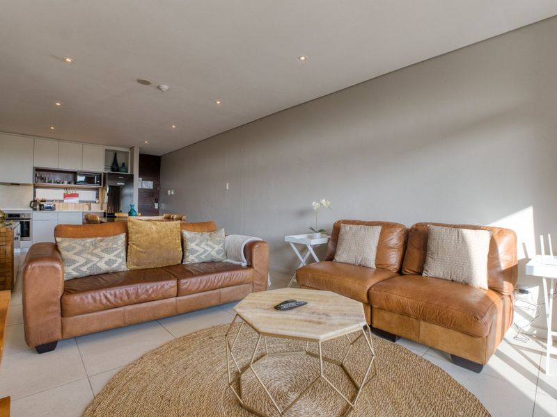 Modern open-plan living area featuring tiled flooring, recessed lighting, and a sleek, well-appointed kitchen with integrated appliances.