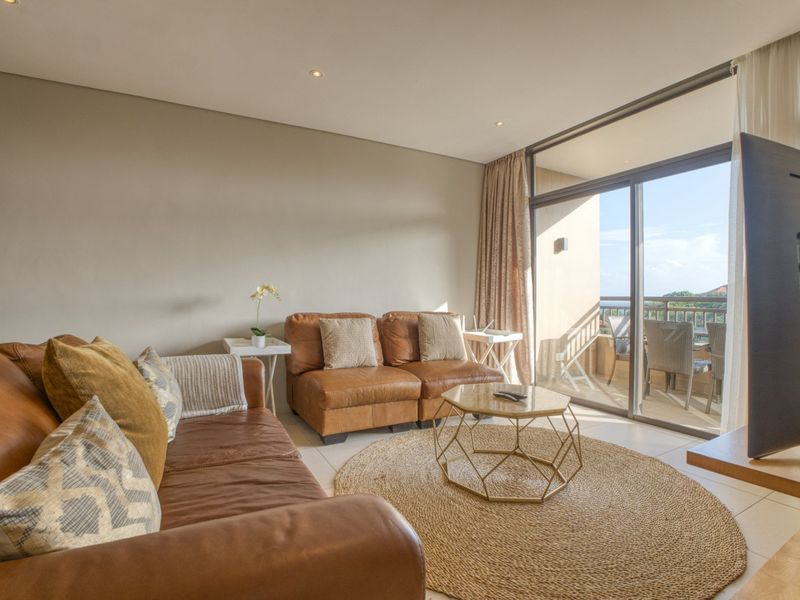 A bright living room featuring tiled flooring, recessed downlights, and large sliding glass doors providing direct access to an outdoor balcony area.