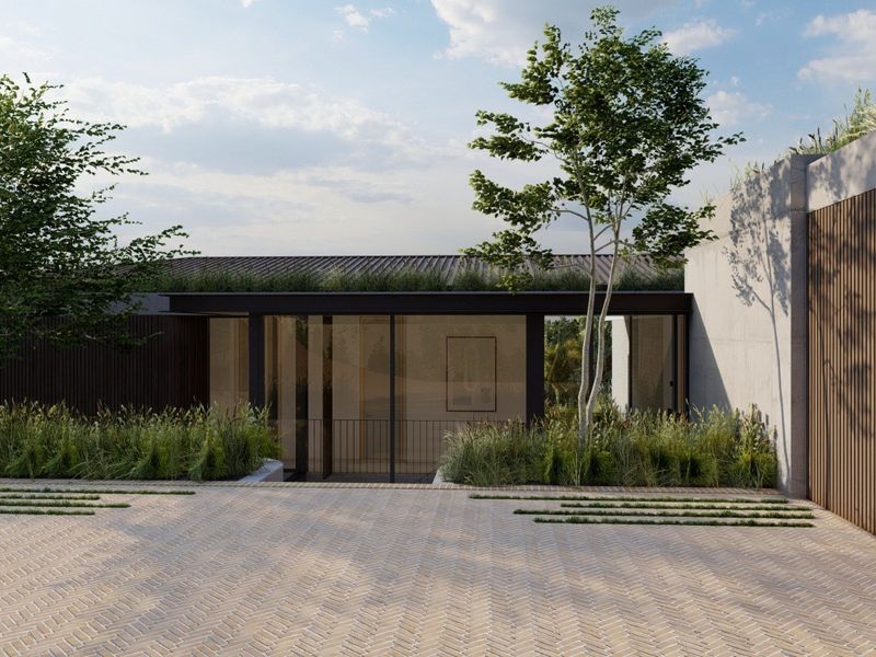 Modern architectural front facade featuring a herringbone brick driveway, green roof, and extensive floor-to-ceiling glass elements with timber slat detailing.
