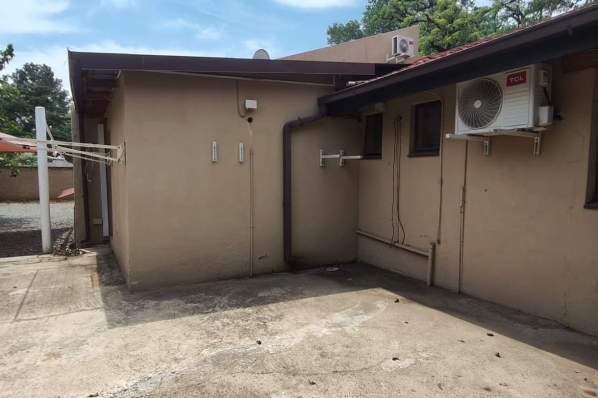 Rear exterior view of the property featuring a concrete patio area, wall-mounted air conditioning units, and external plumbing fixtures.