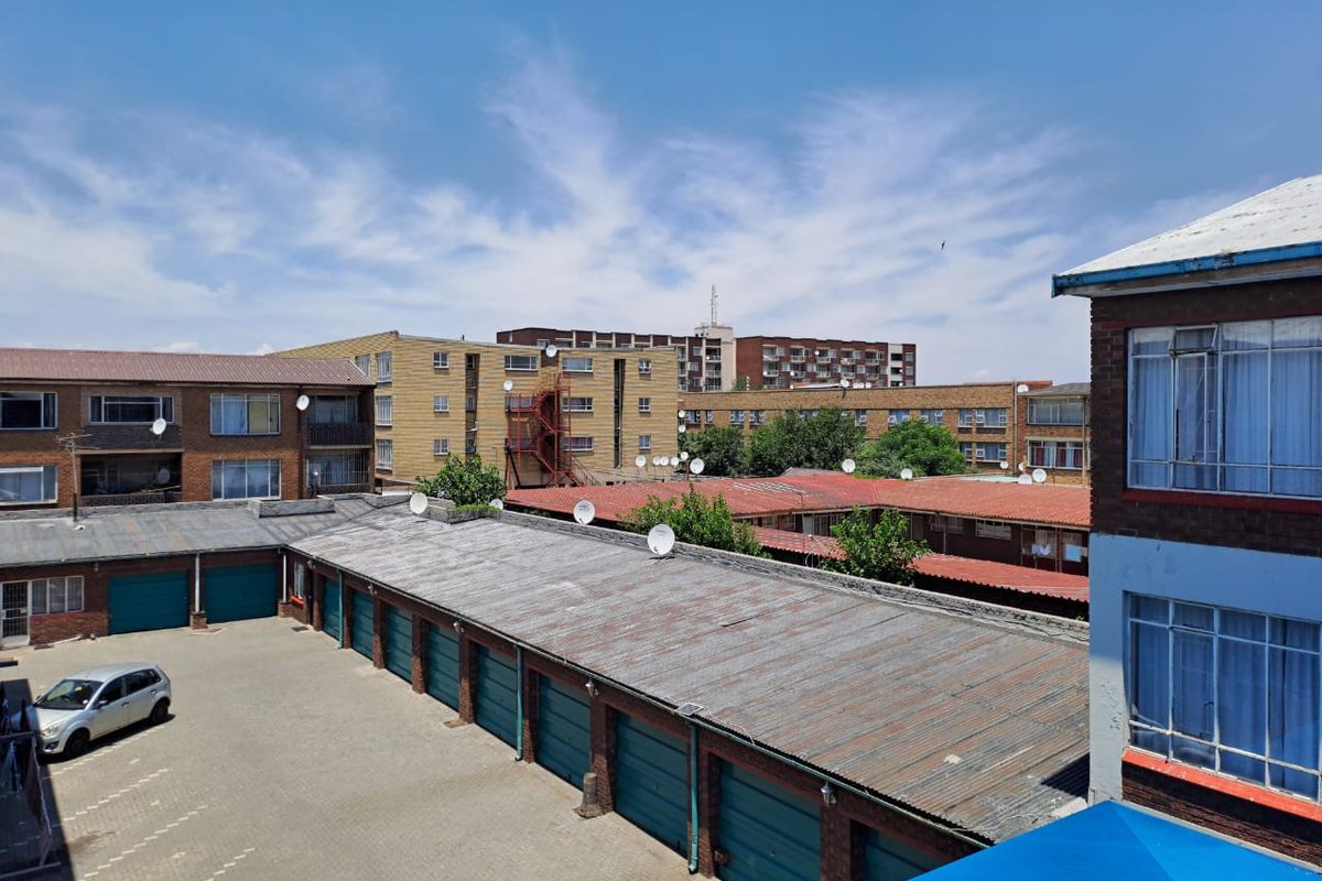 An elevated view of a residential complex courtyard featuring a row of garages with corrugated metal roofing and paved driveway area.
