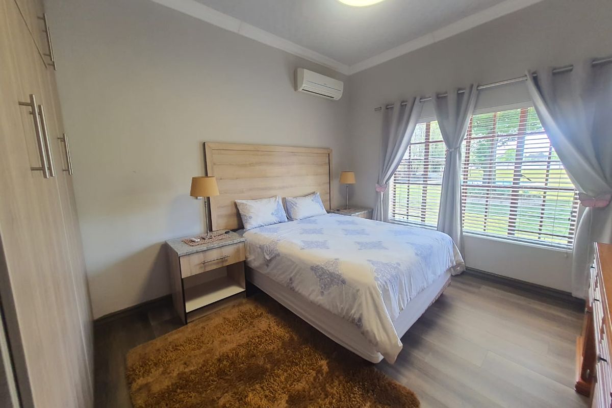 A well-maintained bedroom featuring wood-look flooring, built-in cabinetry, and a wall-mounted air conditioning unit, offering a comfortable and functional living space.