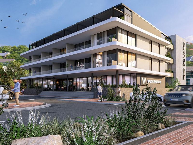 A modern multi-story apartment building featuring contemporary architectural design, glass balconies, and ground-floor retail space in a landscaped urban setting.